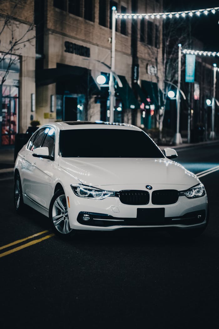 A sleek BMW 3 Series parked on a city street at night, showcasing modern elegance.