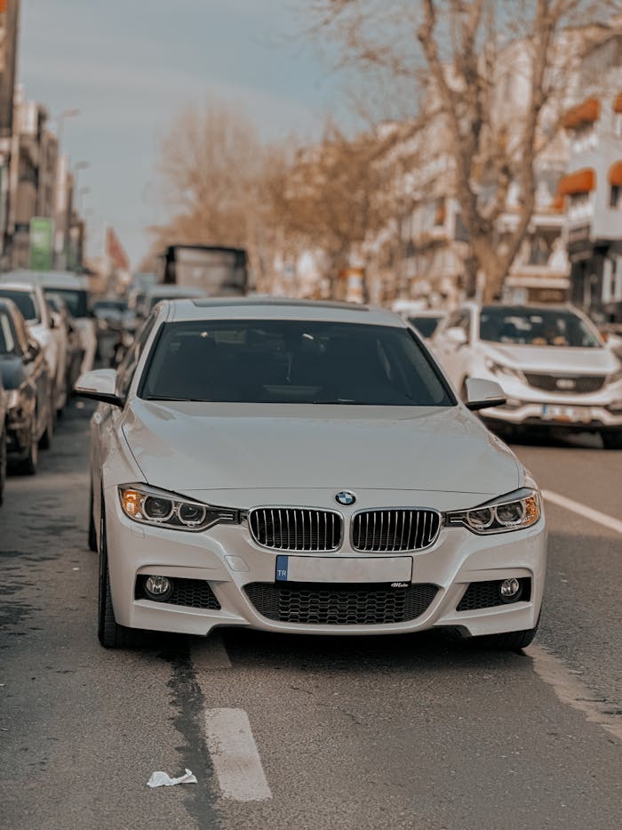 White BMW sports car parked on a bustling urban city street during daytime.