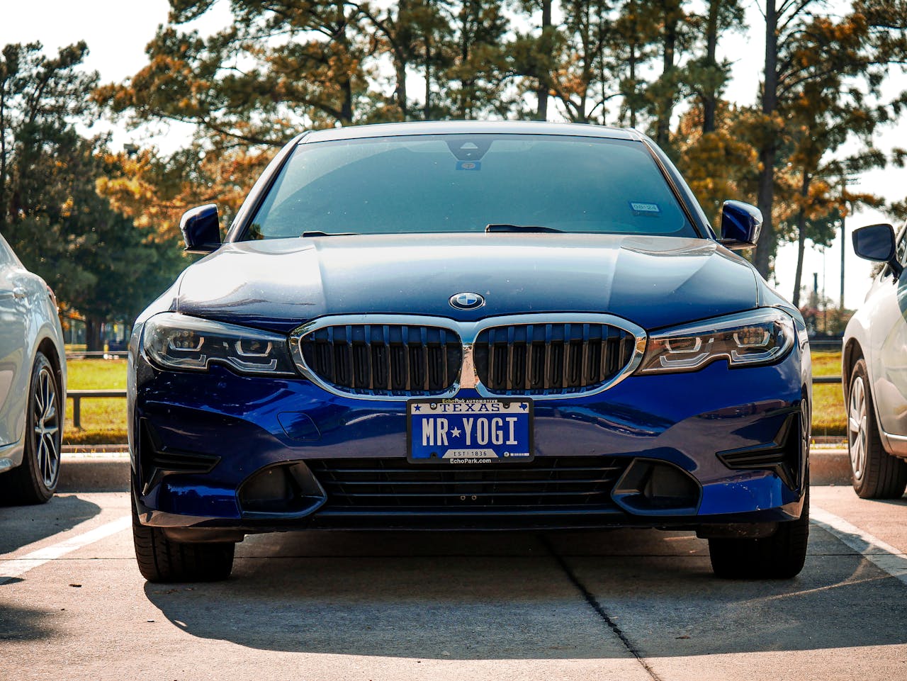 Front view of a blue BMW 3 Series with a custom license plate in Arlington, Texas.