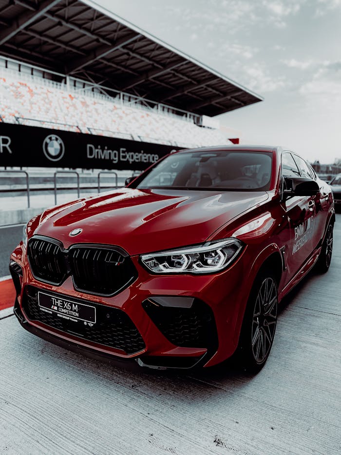 Luxurious red BMW X6 M parked at a track, showcasing style and performance.