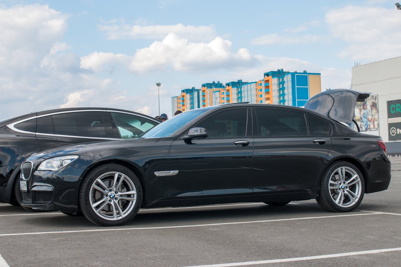 Side view of a sleek black BMW sedan parked in an urban setting with modern buildings.